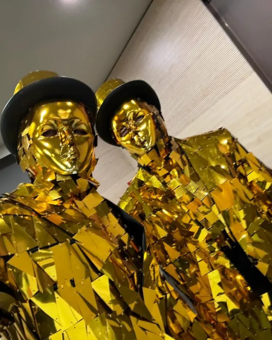 Two golden mirror men in top hats posing at an event