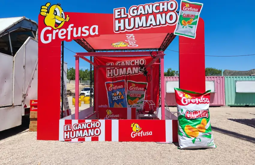 Atracción promocional personalizada de Grefusa con temática de gancho mecánico humano. La estructura roja incluye elementos corporativos de la marca, imágenes de productos y una zona interactiva donde los participantes pueden vivir una experiencia divertida y llamativa durante eventos, ferias y activaciones de marca.