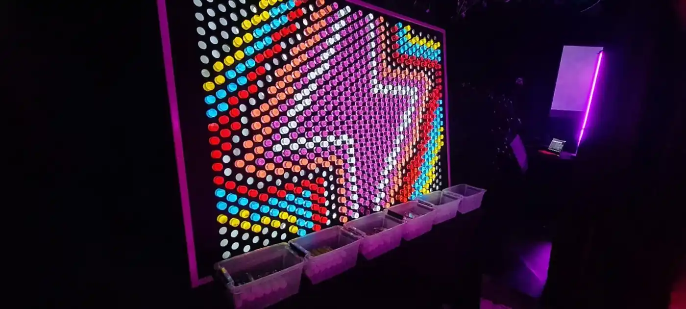 Nens col·locant clavilles de colors en un Lite Brite gegant