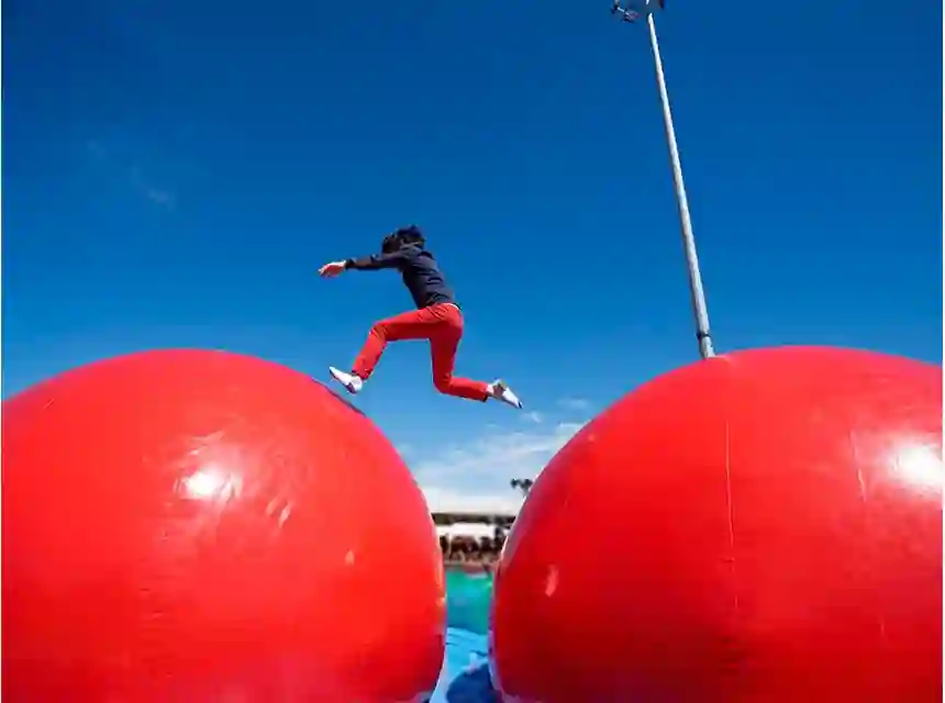 Participant saltant sobre les boles vermelles d'un inflable Wipeout