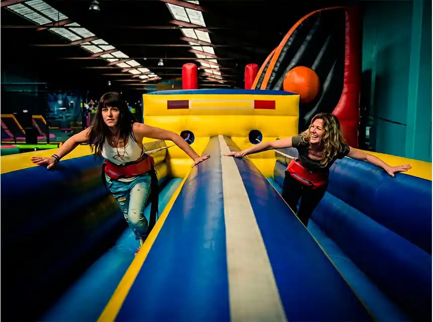 Dos jugadors corrent amb arnès en un bungee run inflable