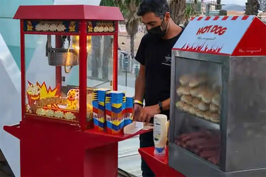 Carro de hot dogs servint en una festa major