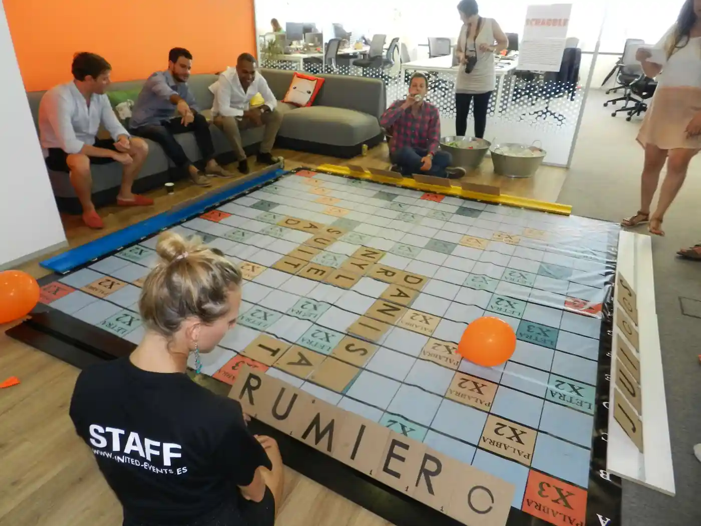 Assistents formant paraules en un Scrabble gegant en un congrés