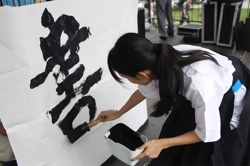 Japanese calligrapher writing names at a trade fair stand
