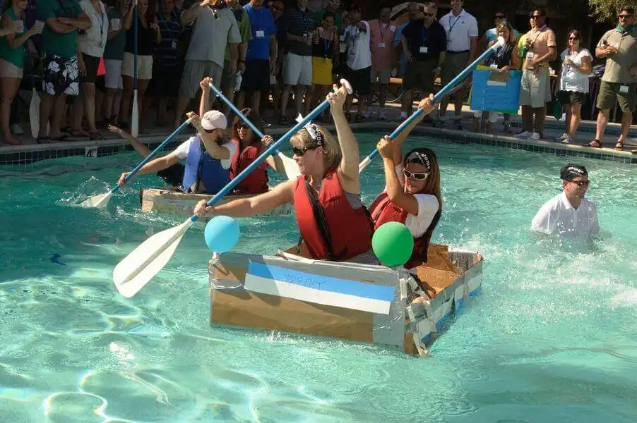 Equipo remando en un barco de cartón en un team building