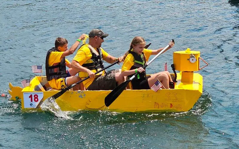 Compañeros construyendo su barco de cartón en la playa