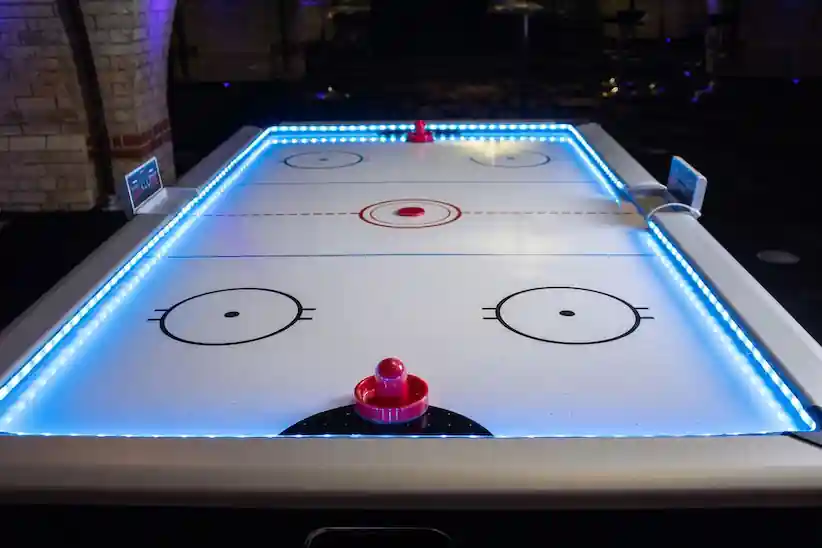 Visitants jugant a air hockey en un estand de fira