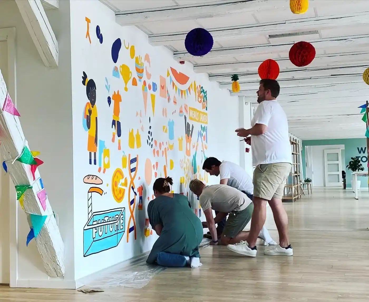 Empleats pintant un mural col·laboratiu en un team building de graffiti