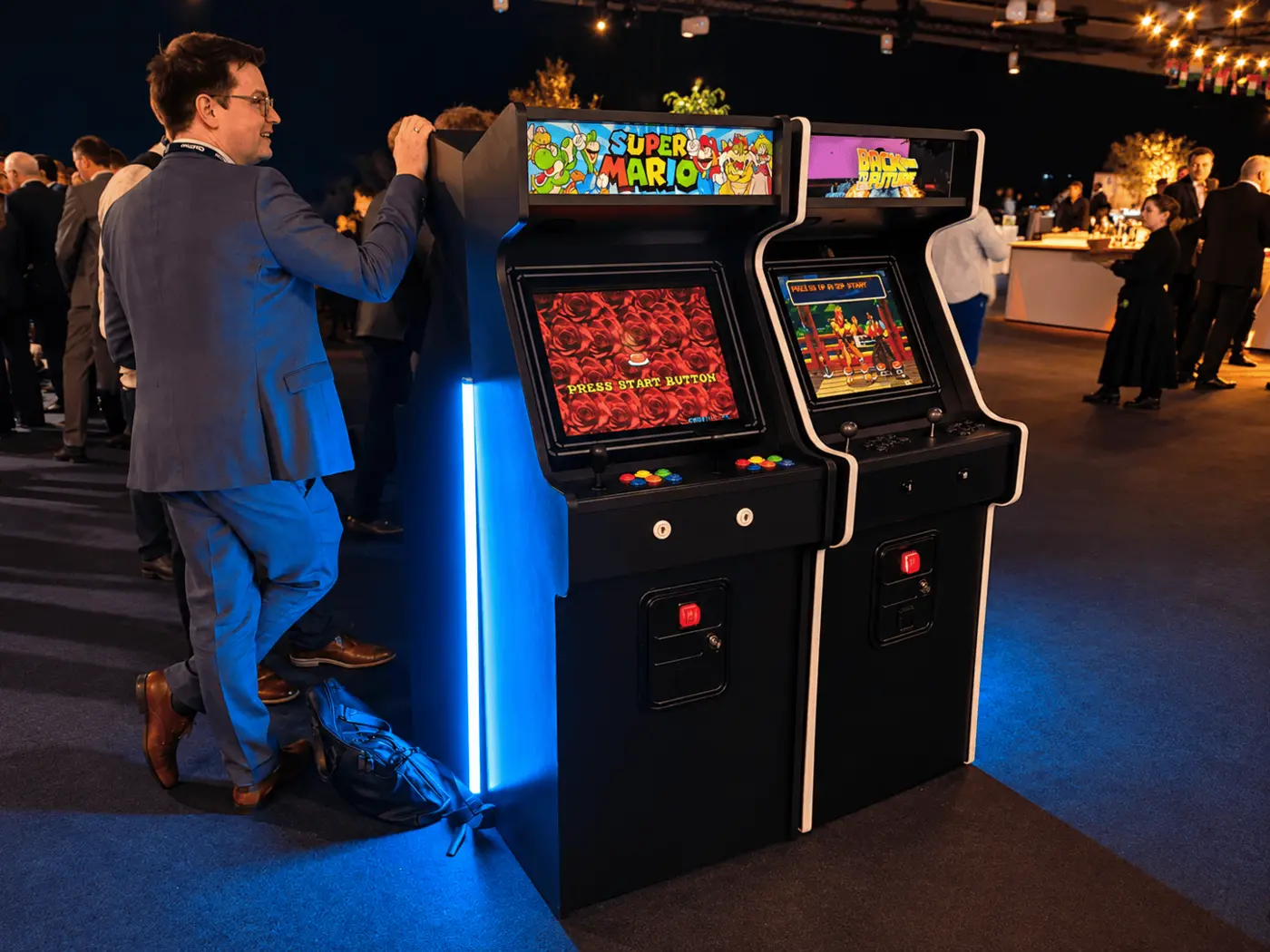Convidats jugant en una màquina arcade en una festa d'empresa