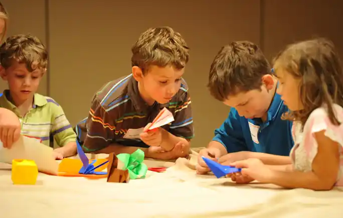 Entertainer teaching origami to children at a communion