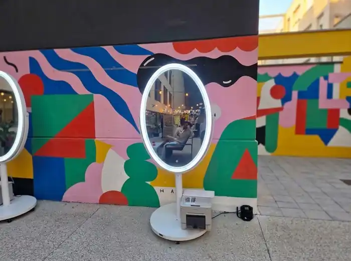 Fotomatón espejo mágico con iluminación LED y cámara integrada instalado en un evento, ideal para capturar fotografías y recuerdos personalizados.