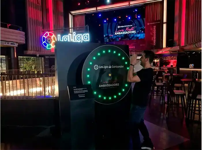 Participante interactuando con un juego de reflejos y velocidad equipado con luces LED en un evento corporativo de LaLiga Santander. La atracción desafía a los asistentes a reaccionar rápidamente ante estímulos luminosos, fomentando la competición, la diversión y la participación en activaciones de marca, congresos, ferias y eventos empresariales.