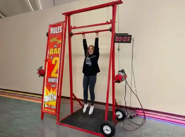 Participante colgada del Reto de la Barra en una prueba de resistencia de un evento temático Juego del Calamar